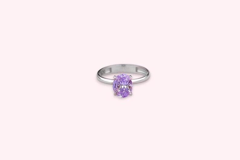 May include: A silver ring with a large oval-shaped purple gemstone.