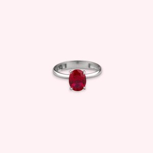 May include: A silver ring with a red oval gemstone.