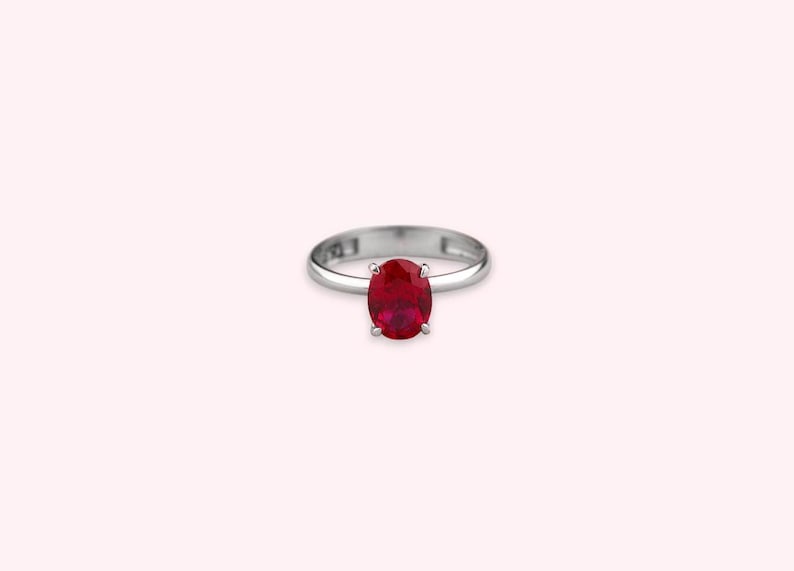 May include: A silver ring with a red oval gemstone.