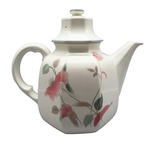 May include: Cream-colored ceramic teapot with a floral design featuring pink flowers and green leaves. The teapot has a curved handle, a spout, and a lid with a small knob. The rim of the lid and the top of the teapot have a blue trim.