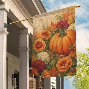 May include: A rectangular garden flag hanging from a gold metal pole, featuring a vibrant autumn scene with a large orange pumpkin, bright orange and yellow daisy-like flowers, clusters of white and deep red hydrangeas, and scattered maple leaves.