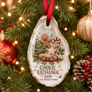 May include: An oyster shell Christmas ornament with a gold-painted edge and a red ribbon hanger. The surface features a gingerbread man, a green Christmas tree, a candy cane, a star, and a rolling pin with a red plaid bow. Text reads COOKIE EXCHANGE 2026 THE MILLER FAMILY.