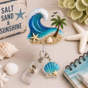 May include: A clear badge reel with a beach scene design. The design features a blue and white wave, a palm tree, a starfish, and a seashell. A smaller seashell and starfish charm hangs below.