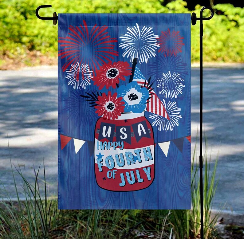 May include: A blue and red garden flag with a mason jar filled with red, white, and blue flowers and fireworks. The jar has the text "USA Happy Fourth of July" on it.