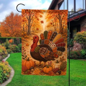 May include: A rectangular garden flag featuring a turkey with a patchwork-style tail made of various plaid and patterned fabrics. The turkey stands on a path surrounded by orange pumpkins, acorns, and autumn leaves in a forest setting.