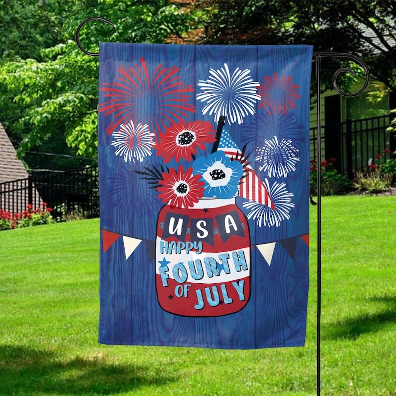 May include: A blue and red garden flag with a mason jar filled with red, white, and blue flowers and fireworks. The jar has the text "USA Happy Fourth of July" on it.