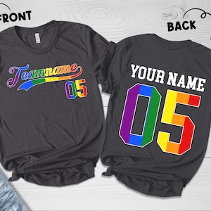 May include: Two dark gray t-shirts with rainbow-colored numbers and text. The front shirt has the text "Teamname 05" in a rainbow-colored arc. The back shirt has the text "YOUR NAME 05" in a rainbow-colored number.