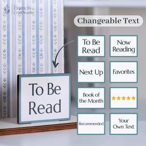 May include: A wooden sign with the text "To Be Read" in a black font, framed with a light blue border. The sign is displayed in front of a book with a blue and white floral pattern. Additional text options include "Now Reading" and "Favorites".