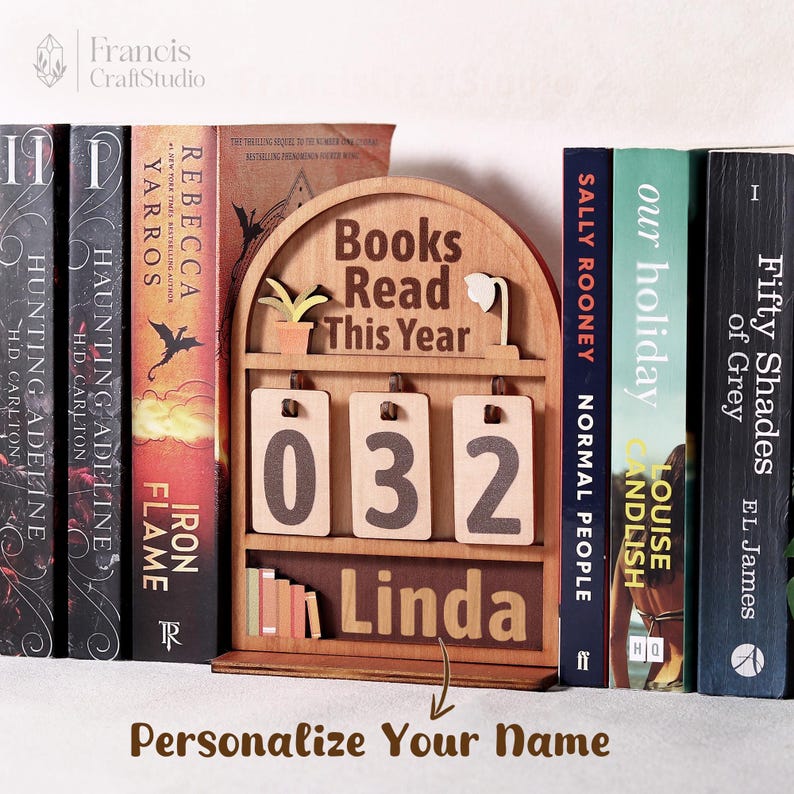 Puede incluir: Un elemento decorativo de estanter&iacute;a de madera con el texto "Books Read This Year" y el n&uacute;mero "032". El nombre "Linda" se muestra debajo de los n&uacute;meros. El texto "Personaliza tu nombre" est&aacute; en la parte inferior.