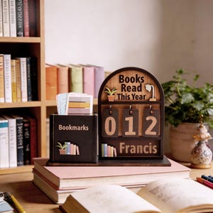 May include: A wooden desk organizer with a bookmark holder and a "Books Read This Year" counter. The counter displays "012" and the name "Francis". The organizer is brown with a bookshelf background.