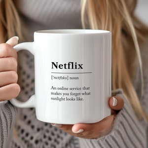 May include: White ceramic mug with a black design that reads "Netflix ['netfliks] noun An online service that makes you forget what sunlight looks like."
