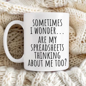 Puede incluir: Taza de caf&eacute; de cer&aacute;mica blanca con texto negro que dice "A veces me pregunto... &iquest;Mis hojas de c&aacute;lculo tambi&eacute;n piensan en m&iacute;?"