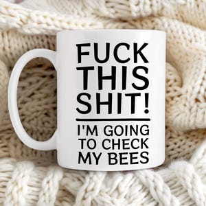 May include: White ceramic coffee mug with black text that reads "F**k this s**t! I'm going to check my bees".