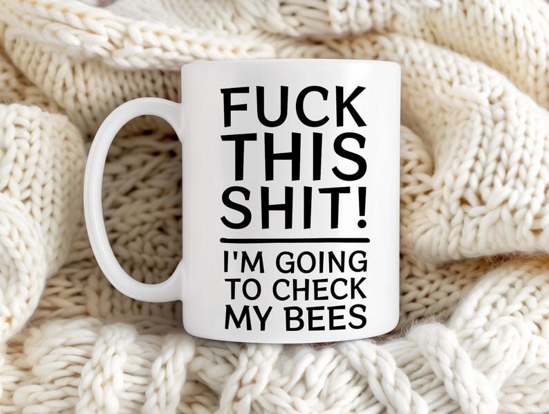 May include: White ceramic coffee mug with black text that reads "F**k this s**t! I'm going to check my bees".