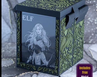 May include: A black and olive green deck box featuring an engraved floral pattern and a front display window showing an elf character card with the text ELF. The box includes a black sword-shaped object and two metallic dice in the foreground.