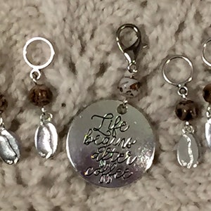 May include: A set of silver-toned coffee-themed charms and stitch markers. The charms feature coffee bean pendants, beaded accents, and a round charm with the phrase "Life begins after coffee."