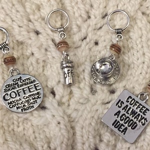May include: Four silver coffee-themed charms with brown and tan beads. One charm has the word "Coffee" with coffee drink terms. Another has a coffee cup, a coffee to-go cup, and a charm that says "Coffee is always a good idea."