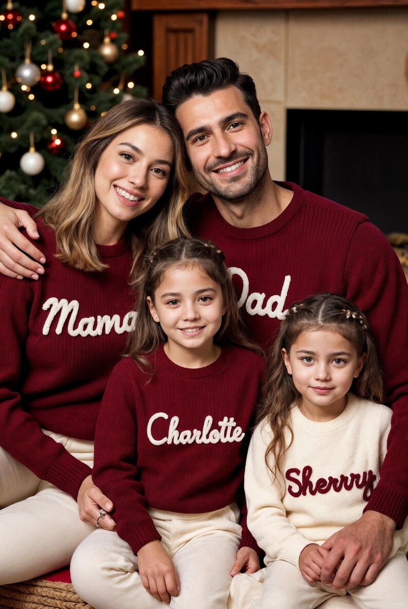 May include: A family of four wearing matching burgundy sweaters with white text. The sweaters read "Mama", "Dad", "Charlotte", and "Sherry". The family is smiling in front of a Christmas tree.