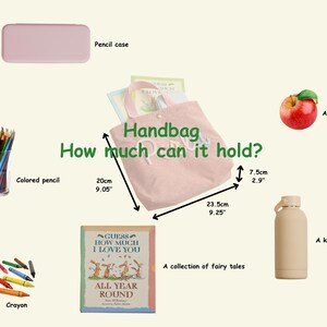 Może przedstawiać: R&oacute;żowa torebka sztruksowa o szerokości 23,5 cm i wysokości 20 cm z napisem "Handbag" i "How much can it hold?". Na zdjęciu znajduje się r&oacute;wnież pi&oacute;rnik, kredki, kredki świecowe, książka, jabłko i czajnik.