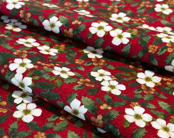 May include: A red fabric featuring a repeating pattern of white five-petaled flowers, dark green holly leaves, and small clusters of golden-brown berries. The textile is folded, creating soft drapes that highlight the floral and botanical print.
