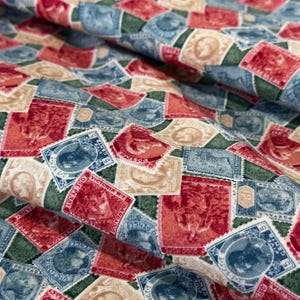 May include: Fabric with a repeating pattern of vintage postage stamps in red, blue, beige, and green. The stamps feature various designs and text, creating a textured and detailed appearance. The fabric is folded, showing depth.