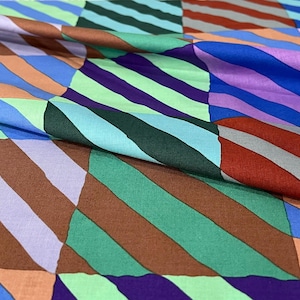 May include: A vibrant fabric with a geometric design. The pattern consists of diagonal stripes in shades of brown, green, purple, blue, and orange. The material appears soft and flowing, suitable for clothing or home furnishings.
