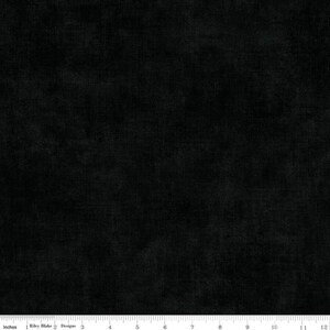 May include: Black fabric with a textured surface. The fabric has a subtle sheen and a soft appearance. The image includes a ruler with inch measurements along the bottom. The text "Riley Blake Designs" is also visible.