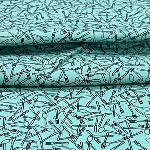 May include: A light teal fabric with a repeating pattern of black line-drawn cutlery, including forks, spoons, and knives. The fabric is folded, showing depth and texture. Ideal for kitchen or dining-themed projects.