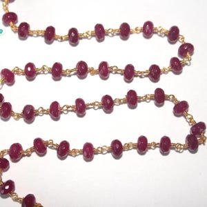 May include: A strand of ruby red faceted beads strung on a gold chain. The beads are approximately 6mm in diameter.