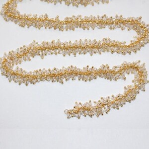 May include: A gold chain with clear crystal beads. The chain is made of small, delicate links and is adorned with tiny, faceted crystals.