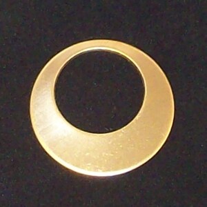 May include: A gold-coloured metal ring with a large, round opening in the centre. The ring is smooth and has a shiny finish.