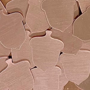 May include: A collection of small, acorn-shaped cutouts in a warm, metallic brown hue. The shapes are scattered, with visible grain and texture, suggesting a natural or rustic theme. Ideal for crafting or decorative projects.