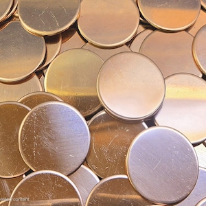 May include: A pile of round, copper-colored metal discs. The discs are smooth and shiny, with a slightly textured surface.
