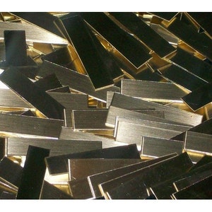 May include: A pile of gold-colored metal strips. The strips are rectangular and have a brushed finish.