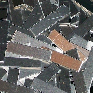 May include: A pile of silver and brown metal strips. The strips are rectangular and have a metallic sheen.