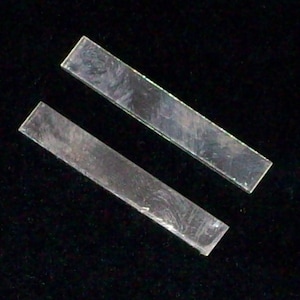 May include: Two clear glass rectangular pieces, possibly for a craft project or jewelry making.