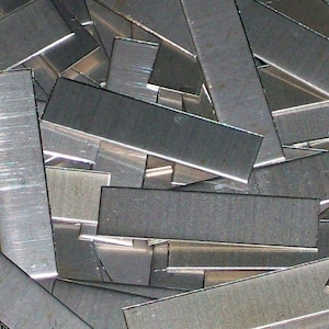 May include: A pile of silver-colored metal strips. The strips are rectangular and have a brushed finish.