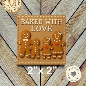 May include: A square magnet featuring a gingerbread family design with the text "BAKED WITH LOVE." The magnet is 2" x 2" and has a light brown background with a wooden pattern. The gingerbread people have white icing details and red heart accents.