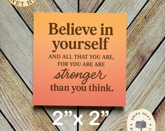 May include: A square magnet with an orange and yellow gradient background. The magnet features the text "Believe in yourself" and "stronger than you think." The magnet measures 2" x 2".