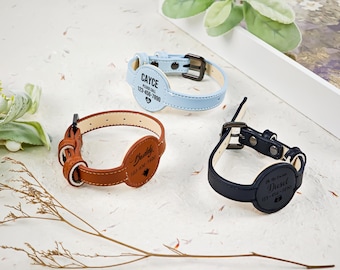 Op de afbeelding: Drie huisdierhalsbanden in lichtblauw, bruin en zwart. Elke halsband heeft een ronde tag met gegraveerde tekst, waaronder namen zoals Cayce, Buddy en Diesel, telefoonnummers en kleine iconen. De halsbanden hebben metalen gespen.