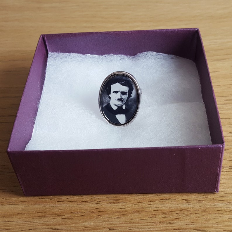 Op de afbeelding: Een zilveren ring met een ovale cameo met een zwart-wit portret van Edgar Allan Poe.