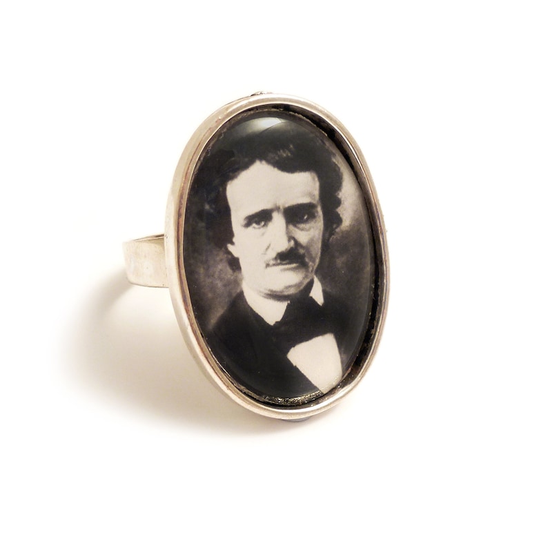 Op de afbeelding: Een zilveren ring met een ovale cameo met een zwart-wit portret van Edgar Allan Poe.