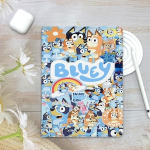 May include: A light blue Bluey-themed notebook featuring various cartoon characters and the word "Bluey" in large, blue letters. The notebook has a rainbow and the text "In My Bluey Era".