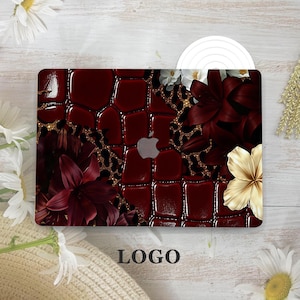 May include: A laptop skin featuring a dark red crocodile skin texture, a black and gold leopard print pattern, and deep red and gold lily flowers. The design includes a central cutout for the silver Apple logo and the word LOGO at the bottom.