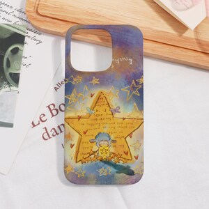 May include: A phone case with a whimsical design. The case features a large yellow star with a sheep illustration and text, surrounded by smaller stars on a purple and gold background.