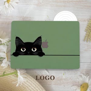 May include: A green laptop skin featuring a black cat peeking over a black line. The cat has large yellow eyes and a small gray Apple logo is visible. The word "LOGO" is printed at the bottom of the skin.
