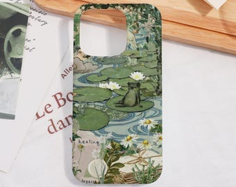 May include: A phone case with a pond design, featuring lily pads, white flowers, and a frog. The case has a watercolour effect with green, blue, and beige tones. The words "healing" and "layers" are printed on the case.