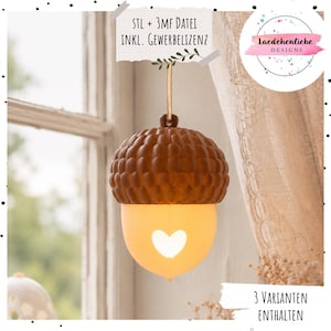 May include: A hanging acorn-shaped ornament featuring a textured brown cap and a smooth, glowing cream-colored base with a heart-shaped cutout. The ornament is suspended by a thin ribbon and includes text reading STL + 3MF DATEI INKL. GEWERBELIZENZ and 3 VARIANTEN ENTHALTEN.