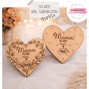May include: Two wooden heart-shaped plaques with engraved text and designs. One plaque features a floral wreath around the word "Mama" and the phrase "Du bist mein... Zuhause." The other has "Mama" and "Du bist mein... Anker."