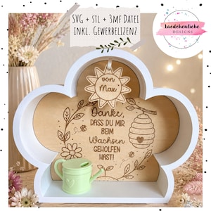 May include: A white cloud-shaped wooden shelf with a light wood back panel featuring laser-engraved text in German, a floral wreath, and a beehive. A small light green plastic watering can sits inside, and a sun-shaped wooden tag reads von Max.